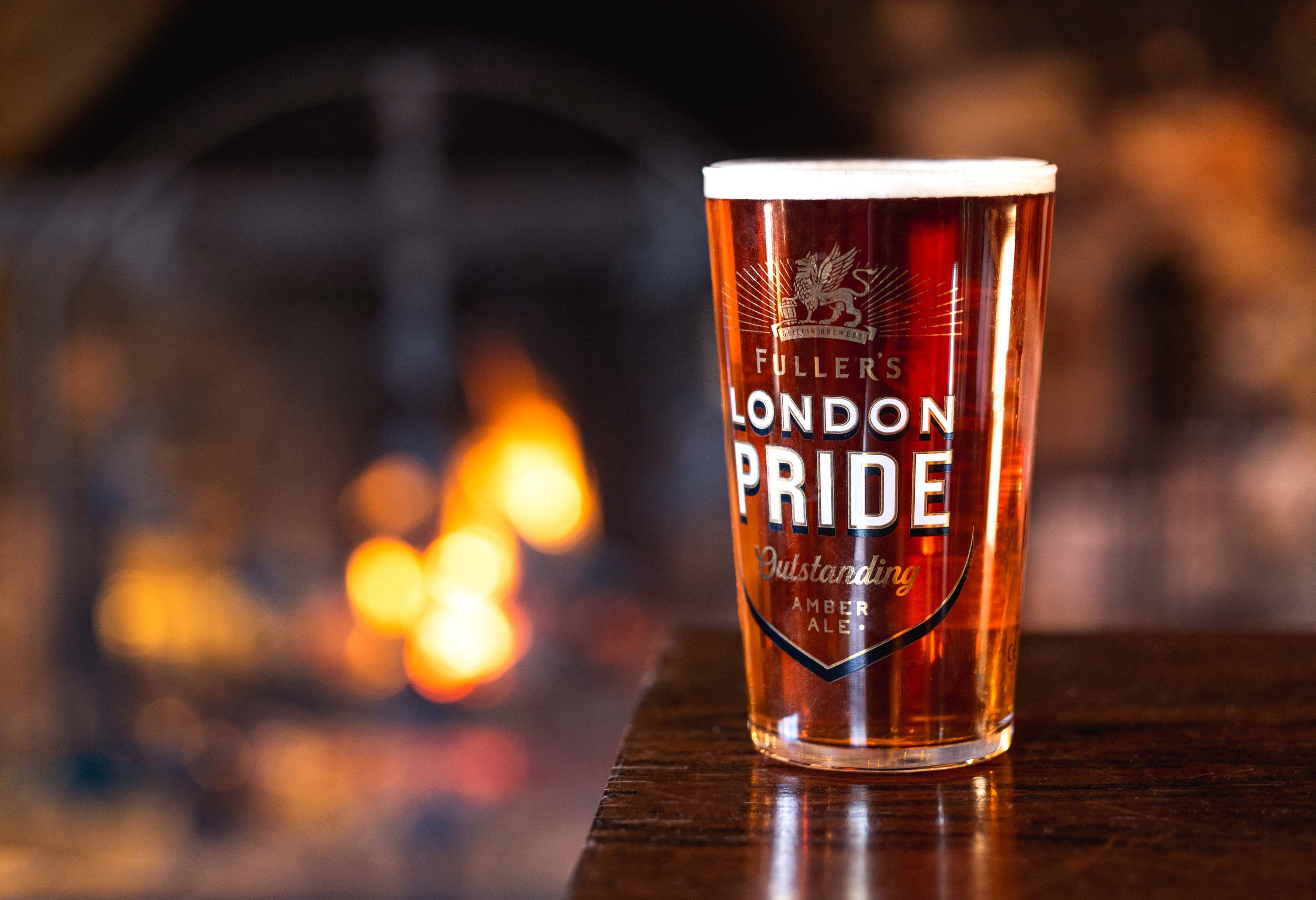 A pint of LOndon Pride next to an open fire